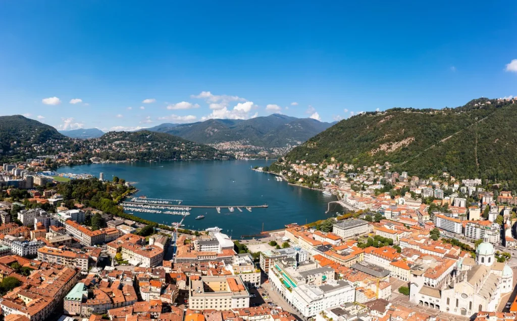 Aerial view of Lake Como and the city of Como on a sunny day, promoted as part of the Como Open Pass travel offer.