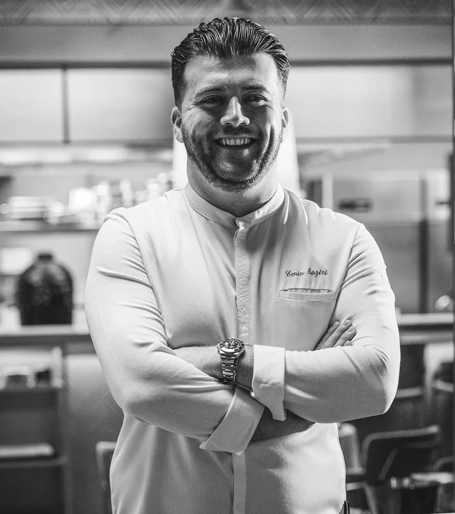 Portrait of Emin Haziri, executive chef of Procaccini Milano, standing in the kitchen with arms crossed.