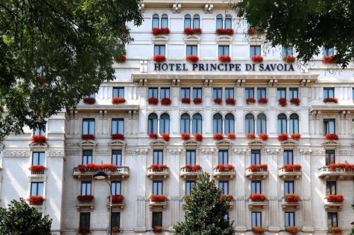 Facade of Hotel Principe di Savoia in Milan, with red geraniums on the balconies
