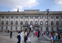 Dalí and Fashion in Milan: Tickets, Hours and What to See Facade of Palazzo Reale on Piazza del Duomo in Milan, with people walking past exhibition banners